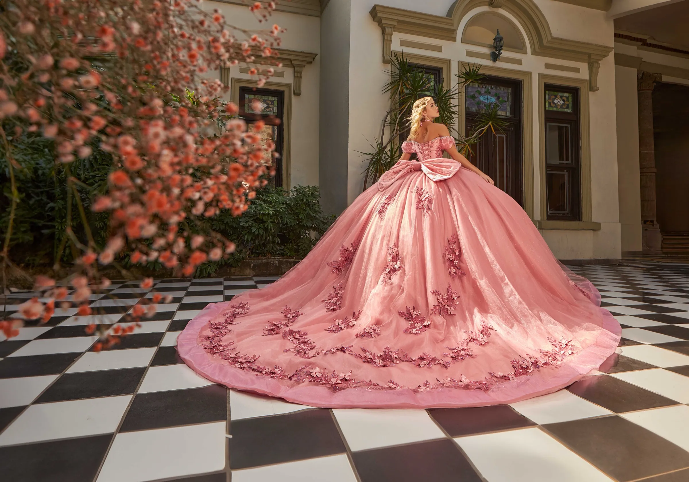 Quinceañera in a pink ballgown on a checkerboard courtyard